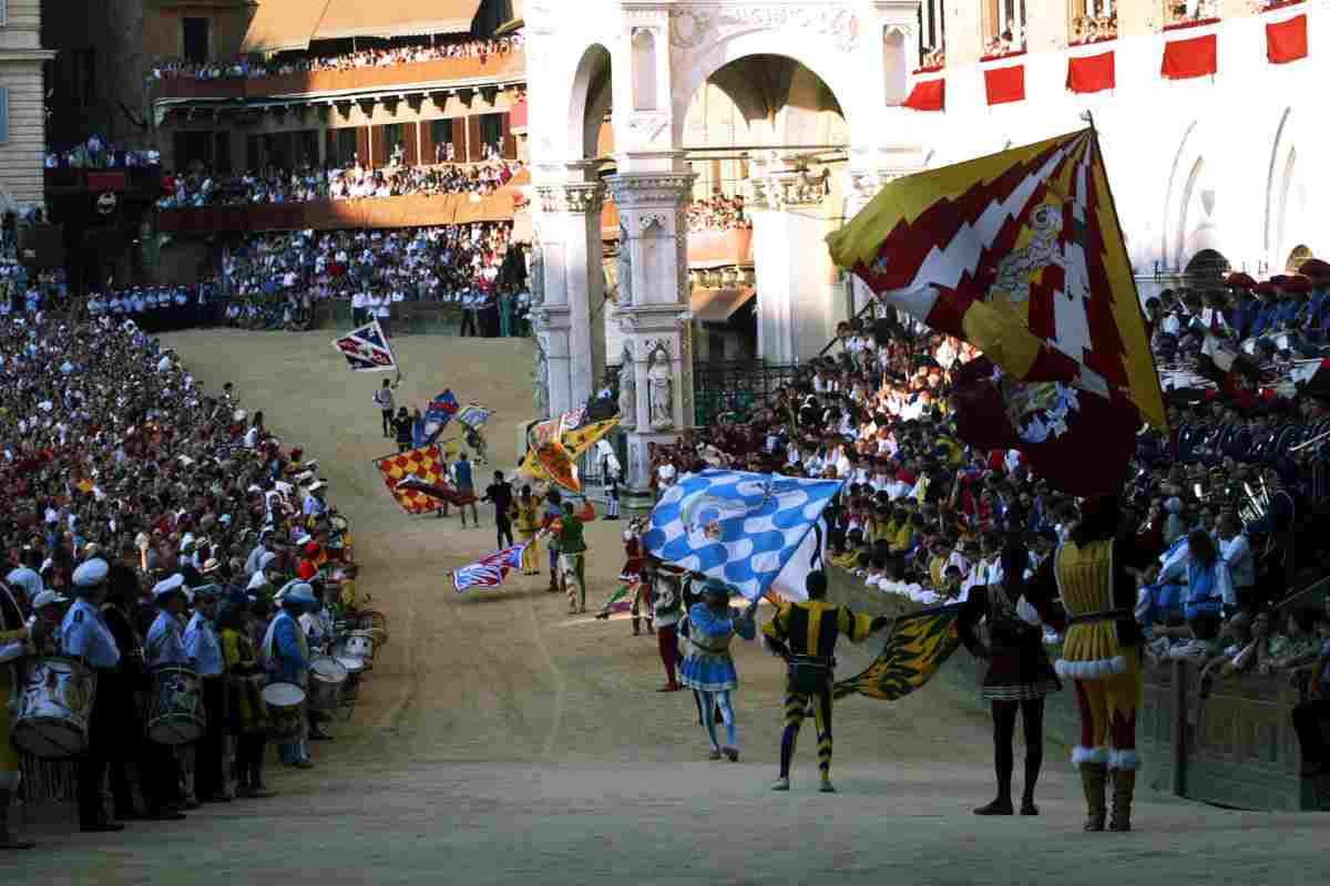 Gli alfieri di tutte le 17 contrade eseguono la sbandierata della vittoria davanti al Palazzo Pubblico prima del Palio. Foto tratta dal libro "Frammenti di Palio"